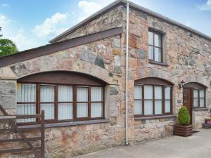 a stone building with large windows on it at Hen Stabl - 16983 in Brynsiencyn