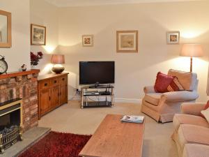 a living room with a fireplace and a television at Lilac Tree Cottage in Dunnington