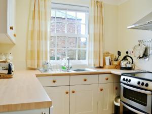 a kitchen with a sink and a stove and a window at Lilac Tree Cottage in Dunnington