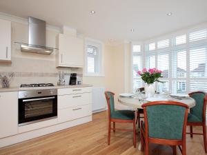 a kitchen with a table and chairs and a kitchen with white cabinets at The Avoncliffe Bournemouth in Southbourne