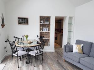 sala de estar con mesa, sillas y sofá en Apple Barn Cottage, en Brixham