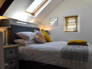 1 dormitorio con cama con almohadas y ventana en Apple Barn Cottage, en Brixham