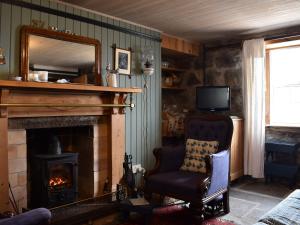 sala de estar con chimenea, silla y espejo en Crovie, en Gardenstown