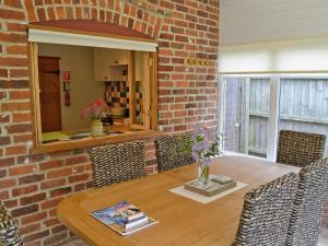 a dining room table with chairs and a brick wall at Briar Cottage in Lessingham