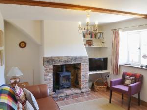a living room with a fireplace and a tv at Briar Cottage in Lessingham