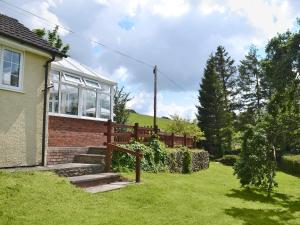 a house with a fence and a grass yard at Mavis Cottage in Kington