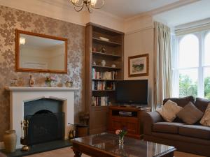 a living room with a couch and a tv and a fireplace at 1 School Cottage in Troutbeck Bridge