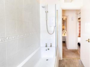 a white bathroom with a tub and a shower at Waters Edge Apartment The Mill in West Burton