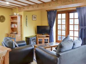 a living room with two couches and a television at The Coach House At Old Vicarage Cottage in Bettws-yn-Rhôs