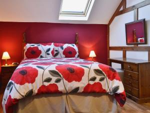 a bedroom with a bed with a red wall at The Coach House At Old Vicarage Cottage in Bettws-yn-Rhôs