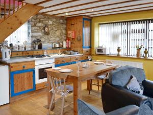 a kitchen with a wooden table and some chairs at The Coach House At Old Vicarage Cottage in Bettws-yn-Rhôs