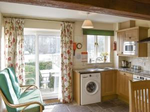 uma cozinha com uma máquina de lavar roupa e uma janela em Stybarrow View Cottage em Glenridding