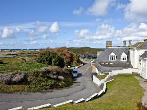 a house with a car parked on a road at Sea Glimpses in Saint Columb Minor