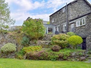 une ancienne maison en pierre avec un jardin en face de celle-ci dans l'établissement Stable Cottage, à Windermere