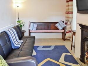 a living room with a couch and a piano at Trecarne Cottage in Saint Cleer