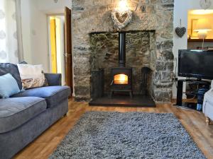 a living room with a couch and a stone fireplace at Didfa - 27912 in Llangoed