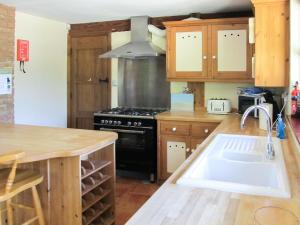 a kitchen with a sink and a stove at Maytree Cottage in East Dereham