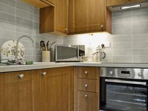 a kitchen with wooden cabinets and a microwave at Hazel Cottage in Ambleside