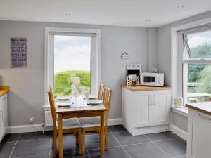 a kitchen with a table and chairs and a microwave at Balcary Mews Cottage in Auchencairn