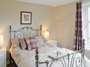 a bedroom with a bed with a plaid pillow at Balcary Mews Cottage in Auchencairn