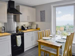 a kitchen with a table and a stove top oven at Balcary Mews Cottage in Auchencairn