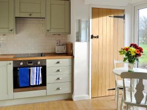 a kitchen with green cabinets and a white refrigerator at Chorlton Moss Cottage in Maer