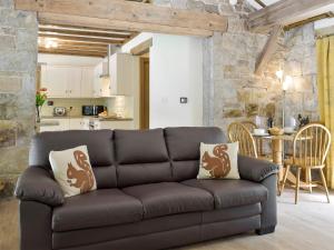 a living room with a brown couch and a kitchen at The Coach House At Stable Cottage in Derwydd