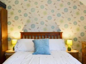 ein Schlafzimmer mit einem Bett mit einem blauen Kissen darauf in der Unterkunft Chorlton Moss Cottage in Maer