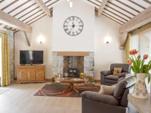 a living room with a fireplace and a clock on the wall at The Coach House At Stable Cottage in Derwydd