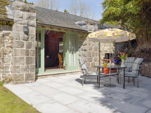 un patio con mesa y sombrilla en The Coach House At Stable Cottage, en Derwydd