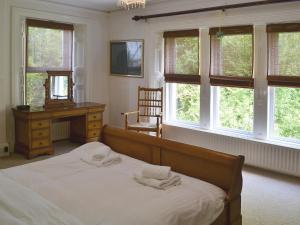 a bedroom with a bed and a desk and windows at Holly Lodge in Gilcrux