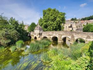 uma ponte sobre um rio em frente a uma cidade em The Coach House em Tytherton Lucas