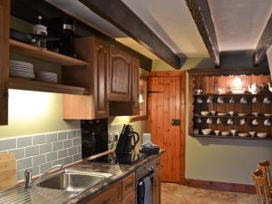 una cocina con armarios de madera y fregadero en Craigdarroch Cottage en Strathyre