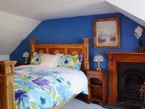 1 dormitorio azul con 1 cama y chimenea en Craigdarroch Cottage en Strathyre
