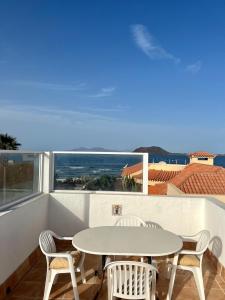 a table and chairs on a balcony with a view of the ocean at Pura Vida Surf Camp & School in La Oliva