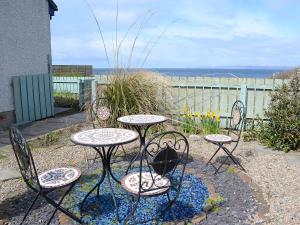 a patio with three chairs and a table and two tables at Larachan in Scarfskerry