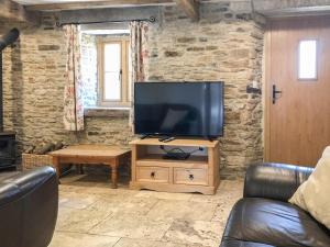 a living room with a flat screen tv on a wooden stand at Tawny Owl Barn in Barlow