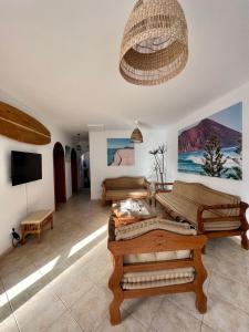 una sala de estar con muebles de madera y una lámpara de araña. en Pura Vida Surf Camp & School, en La Oliva