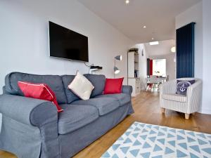 a living room with a blue couch with red pillows at Above Towan At 8 Quay Court in Newquay