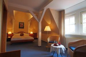 um quarto com uma cama, uma cadeira e uma mesa em Hotel Schlossvilla Derenburg em Derenburg