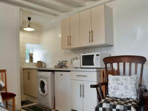 a kitchen with a washing machine and a microwave at Heckberry Cottage in Burtree Ford