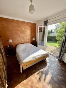 um quarto com uma cama e uma grande janela em Les orangers - Villa catalane avec Jacuzzi em Saint-Génis