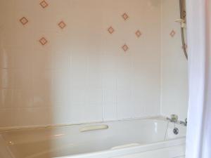 a bath tub in a bathroom with white tiles at The Cider Mill Cottage in Orleton
