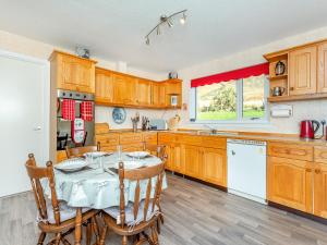 a kitchen with wooden cabinets and a table with chairs at West Home in Torridon