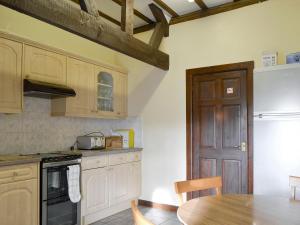 - une cuisine avec des placards en bois, une table et un réfrigérateur dans l'établissement Grove Sprightly Barn, à Craven Arms