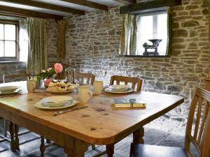 a wooden table in a room with a stone wall at Boundstone Farmhouse in Littleham