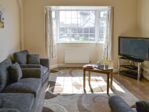 a living room with a couch and a tv and a table at Dune Cottage in Caister-on-Sea