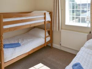 a bedroom with two bunk beds and a window at Dune Cottage in Caister-on-Sea