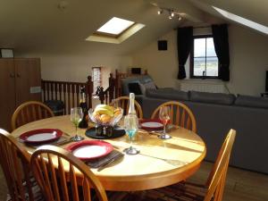 a wooden table with chairs and a table with wine glasses at Jenlea Cottage in Grizebeck