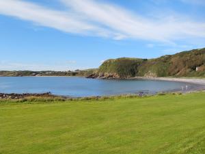 a body of water with a green field and a beach at Knock School Cottage in Monreith